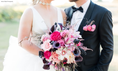Bride and groom pictured with various shades of pink wedding flowers.